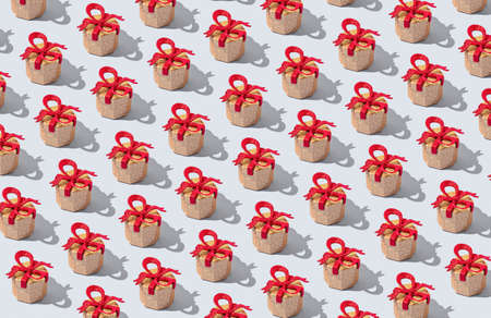 Creative pattern made with glittering golden present boxes with red bows on pastel background. Christmas or birthday gift concept. Holiday theme. Minimal style.の写真素材