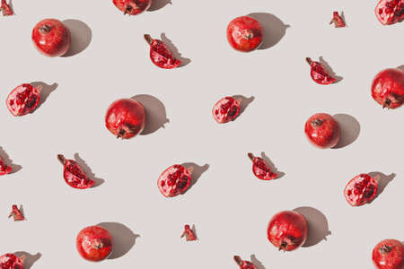 Creative pattern made of fresh pomegranates on pastel gray background with sunlit. Minimal style. Top view. Flat lay.の写真素材