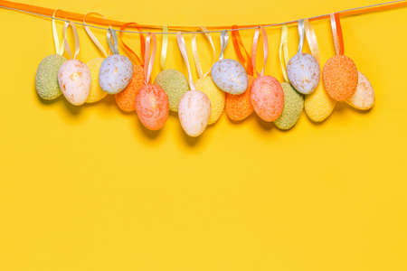 Decorative easter eggs hanging on a strip next to yellow background. holiday concept. Minimal styleの写真素材