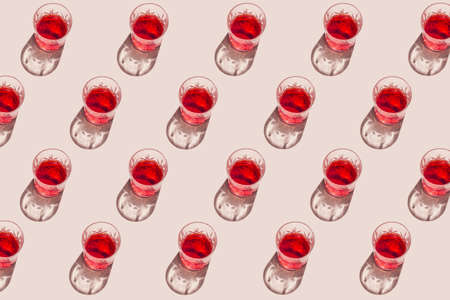 Creative pattern made of glass with red juice on pastel gray background. Summer refreshment concept. minimal style. Sunlit flat lay. top viewの写真素材