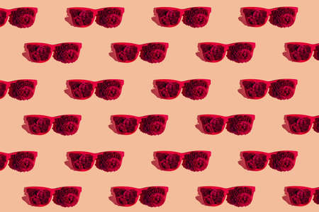 Creative pattern made of red sunglasses with rose buds on pastel background. Summer fashion concept. minimal style. top view. flat layの写真素材