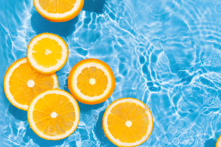 Creative summer composition made of sliced orange in transparent pool water. Refreshment concept. Healthy refreshing drink theme. top viewの写真素材