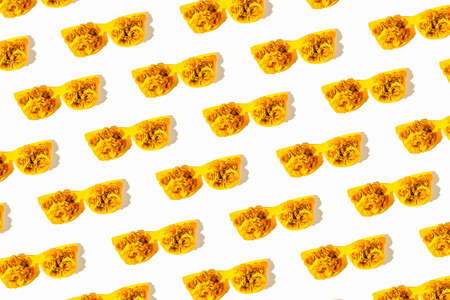 Creative pattern made of yellow sunglasses with beautiful rose buds on white background. Summer fashion concept. beauty and accessories theme. minimal style. top view. flat layの写真素材