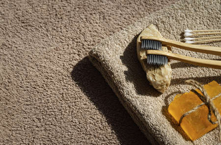 Creative layout made of two toothbrushes, natural soap and cootton buds on sunlit background with towels. Morning routine concept. top view. flat layの写真素材