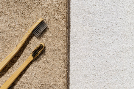Creative layout made of two toothbrushes on beige towel with white sunlit background . Morning...