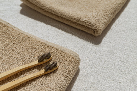 Creative layout made of two toothbrushes on beige towel with white sunlit background . Morning routine concept. Minimal styleの写真素材