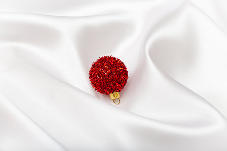 Creative background made of red decorative bauble and white silk sheet. Minimal style composition. Christmas and New Year conceptの写真素材