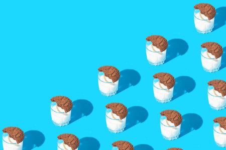 Creative pattern made of brown american cookies on a glass of milk on blue background. minimal...