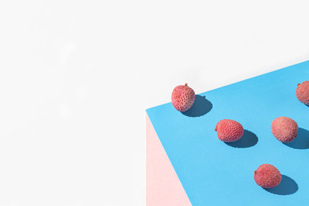 Minimal style composition made of fresh lychee fruits on colorful geometric background. Healthy food concept. Summer refreshment themeの写真素材