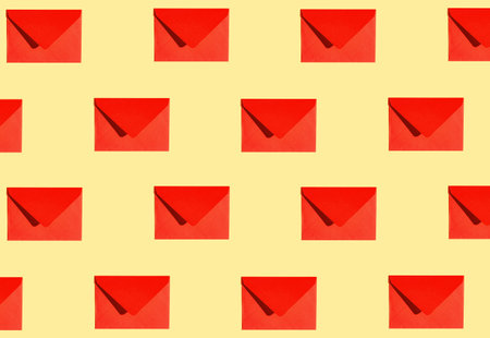 Creative pattern made of red paper envelope on yellow background. minimal style. Greeting letter and mail concept.の写真素材