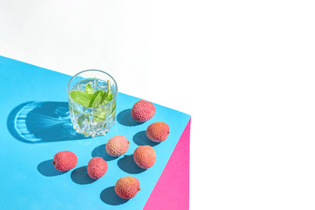 Creative still life composition made of glass with lemonade and lychee fruits on colorful background. Summer refreshment concept.の写真素材