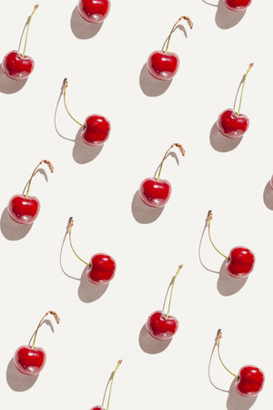Minimal style pattern made of fresh red cherries on white sunlit background. Healthy food concept.