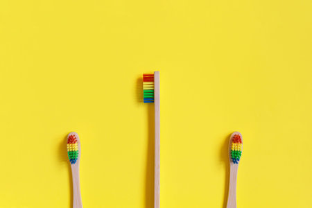 Creative layout made of three toothbrushes on bright yellow background. Morning routine concept....