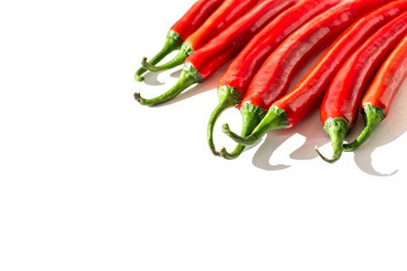 Creative composition made of red chilli peppers on white sunlit background with shadow. Healthy food ingredient concept. Selective focusの写真素材
