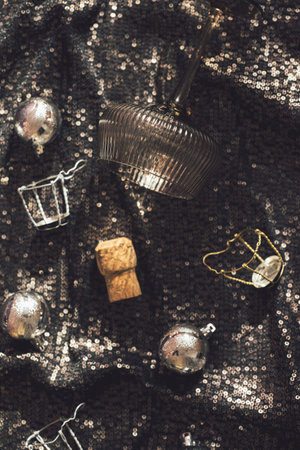 Stylish glass for cocktail, champagne corks and Christmas balls on shimmering fabric background. Xmas and new year celebration concept. Festive and party themeの写真素材