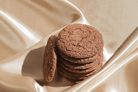 Brown american cookies on beige silk fabric background. Minimal style. Bakery and pastry concept.の写真素材