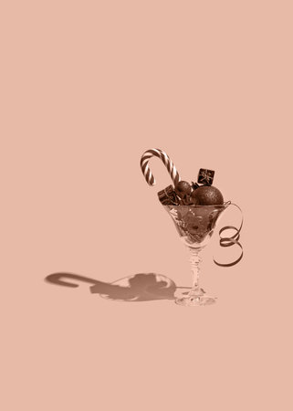 Creative composition made of martini glass with decorative baubles, present boxes and lollipop on pastel background. Party and festive concept. Minimal style. Color of the year 2025 inspiredの写真素材