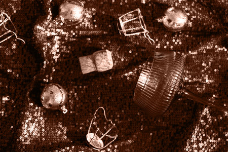 A glass for cocktail, champagne corks and Christmas balls on shimmering fabric background. Xmas and...