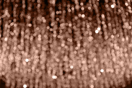 Defocused glittering background of golden garland lights on city street. Abstract blurry bokeh backdrop. Holiday concept.の写真素材