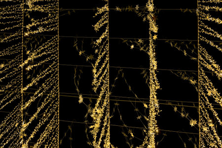 Defocused glittering background of golden garland lights on city street. Abstract backdrop. Holiday conceptの写真素材