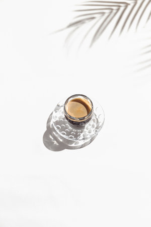 A cup of coffee on white background with palm tree leaf shadow. Minimal styleの写真素材