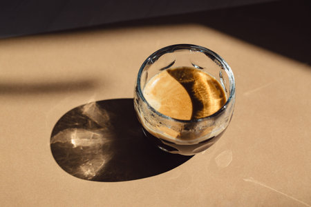 A cup of coffee on beige background with shadow. Minimal style.