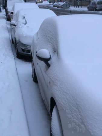 Car covered with snow in the city during a heavy snowfall.の写真素材