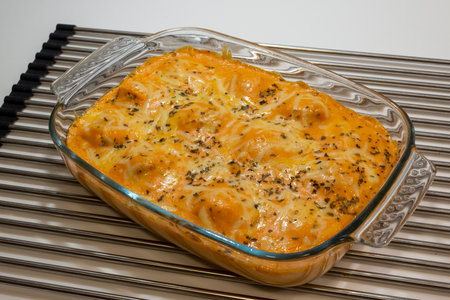 Baked lasagna with cheese and herbs in a glass baking dishの写真素材