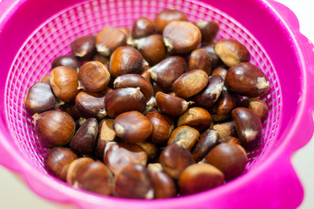Fresh chestnuts in a pink colander, shallow depth of fieldの写真素材