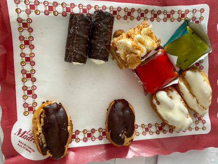 Assorted eclairs on a white plate with a red backgroundの写真素材