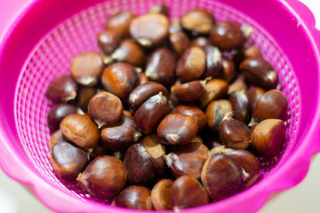 Fresh chestnuts in a pink colander on a white background.の写真素材