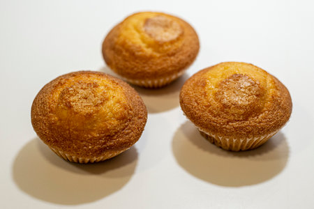 Three muffins with sugar on a white background, close-upの写真素材