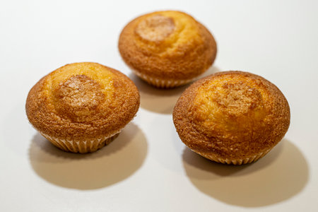Three freshly baked muffins on a white background with hard shadows.の写真素材