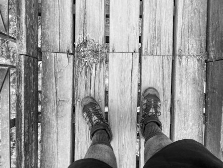 Selfie of legs in boots on a wooden bridge. Black and white.の写真素材