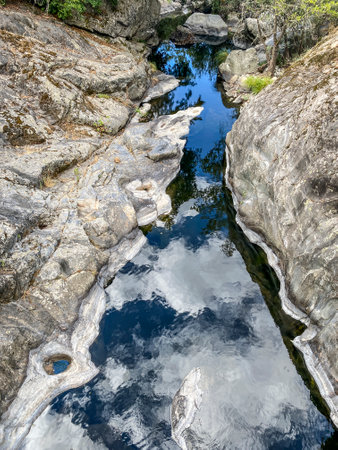 River in the mountains with clear water and reflections on the stones.の写真素材