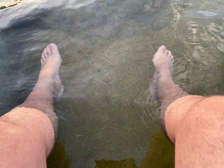 Legs of a man in the water of a lake, close-upの写真素材