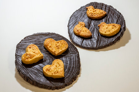 Heart shaped cookies on a black wooden plate on a white background.の写真素材