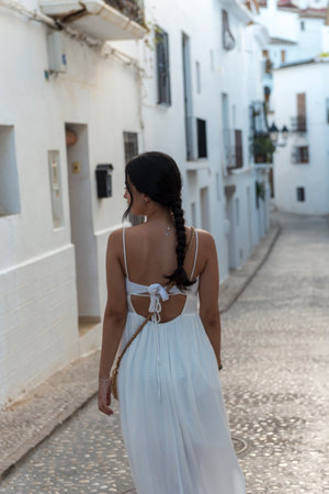 Back view of a beautiful woman in white dress walking on the streetの写真素材