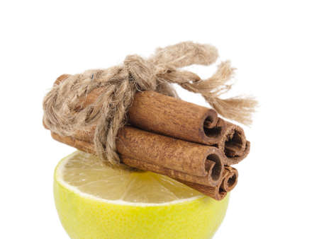 half of a lime and on this half slices of cinnamon are connected by a ropeの写真素材