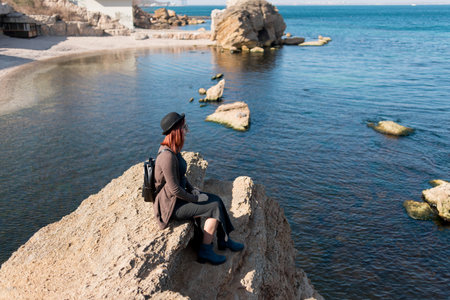 Girl traveler sits on a rockの写真素材