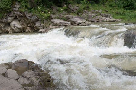 Against the background of the wood and stones the river flows small, but rough,の写真素材