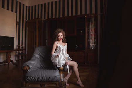 young, sexy, positive girl sitting on the couch it is in the roomの写真素材