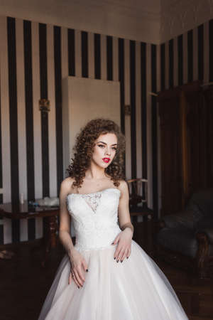 portrait of a curly bride who stands in a room by the windowの写真素材
