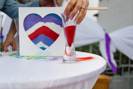the hand takes a vessel with colored sand to pour it into another vessel during the wedding ceremonyの写真素材