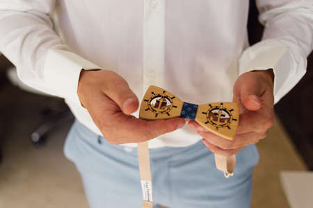 The male hands of the groom hold a butterfly from the tree on which the sea anchor is carvedの写真素材