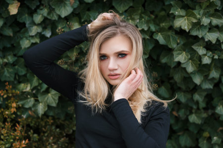 photo of a very beautiful girl on a background of a plant with an expressive and charming look