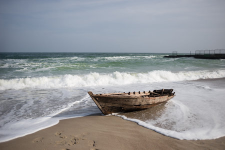 the sea during the storm covers the waves of an old small wooden boat on the shore