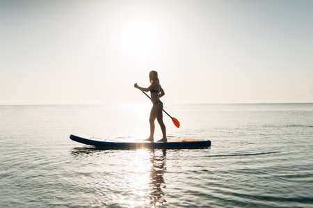 Stand up paddle board woman paddleboarding on Hawaii standing happy on paddleboard on blue water.の写真素材