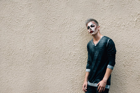 A young guy with a beautiful appearance is preparing for a party in honor of Halloween