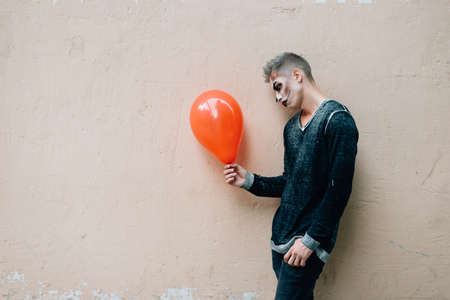 The guy is standing in profile and holding an orange balloonの写真素材